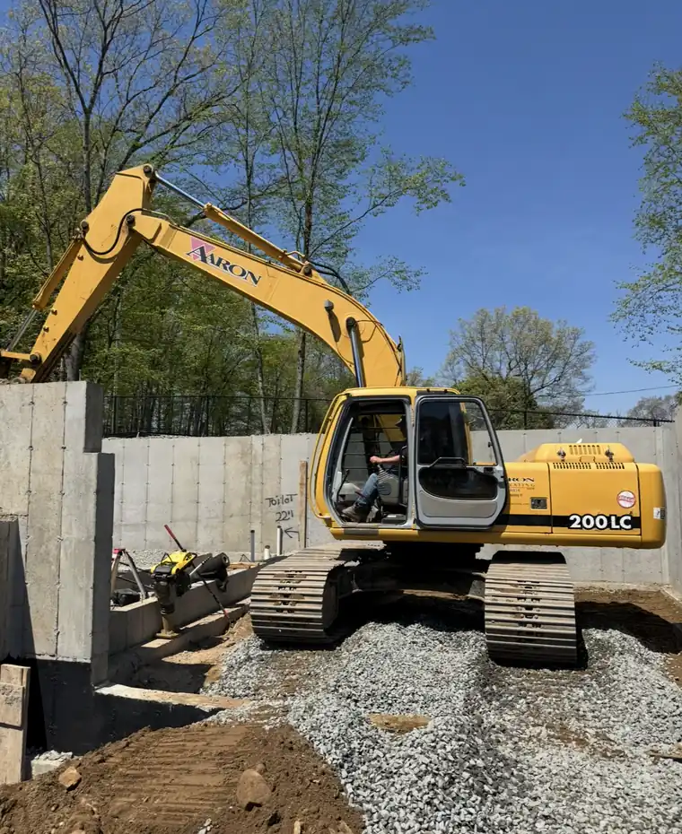 Aaron Excavating excavator preparing a building pad inside new foundation walls