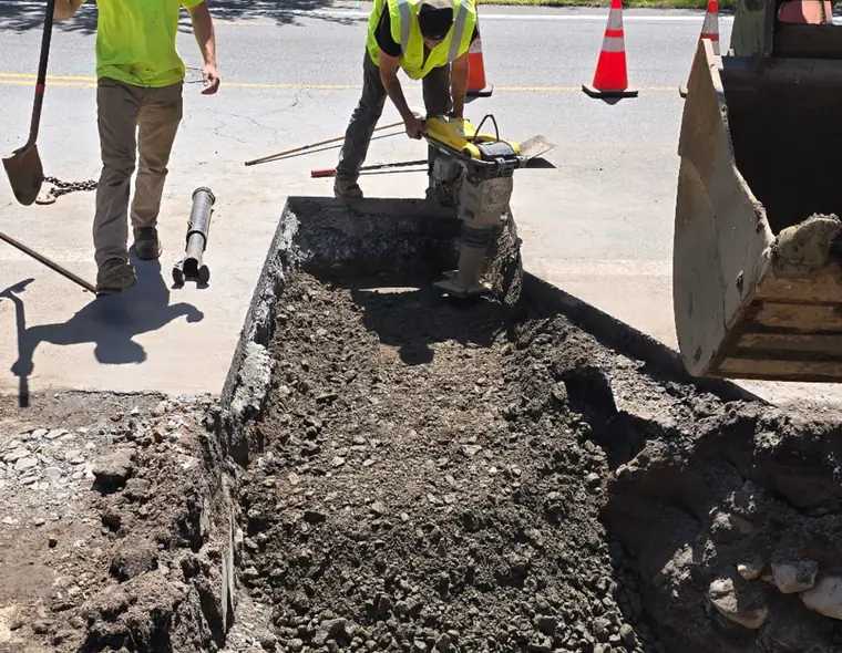 Crew compacting stone and backfill after a line repair