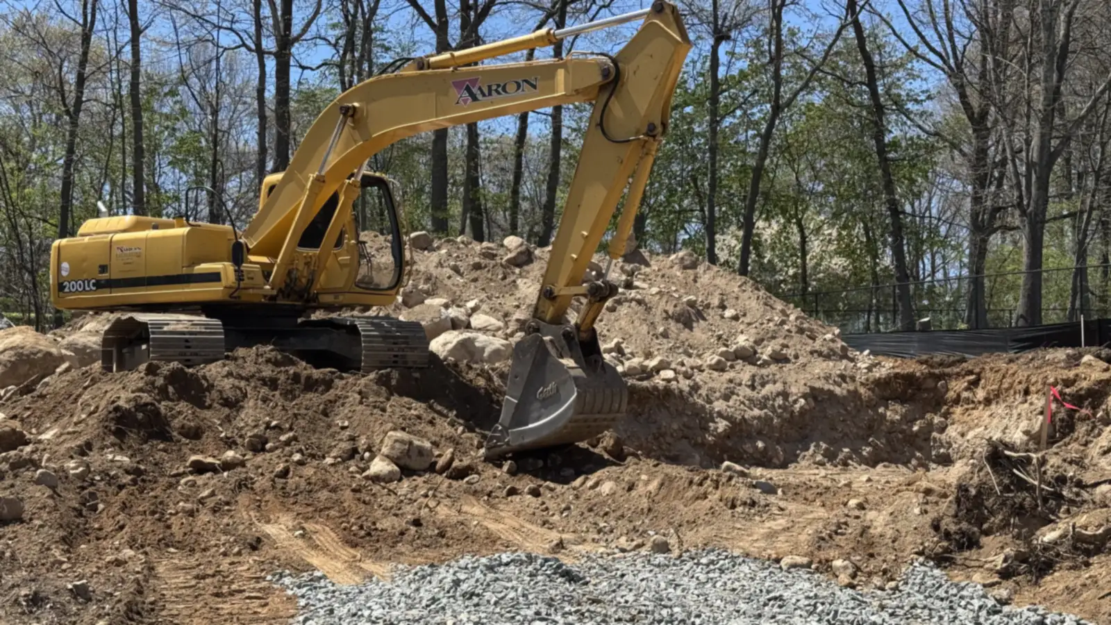 Aaron Excavating excavator digging on a wooded property — pond excavation contractors near me
