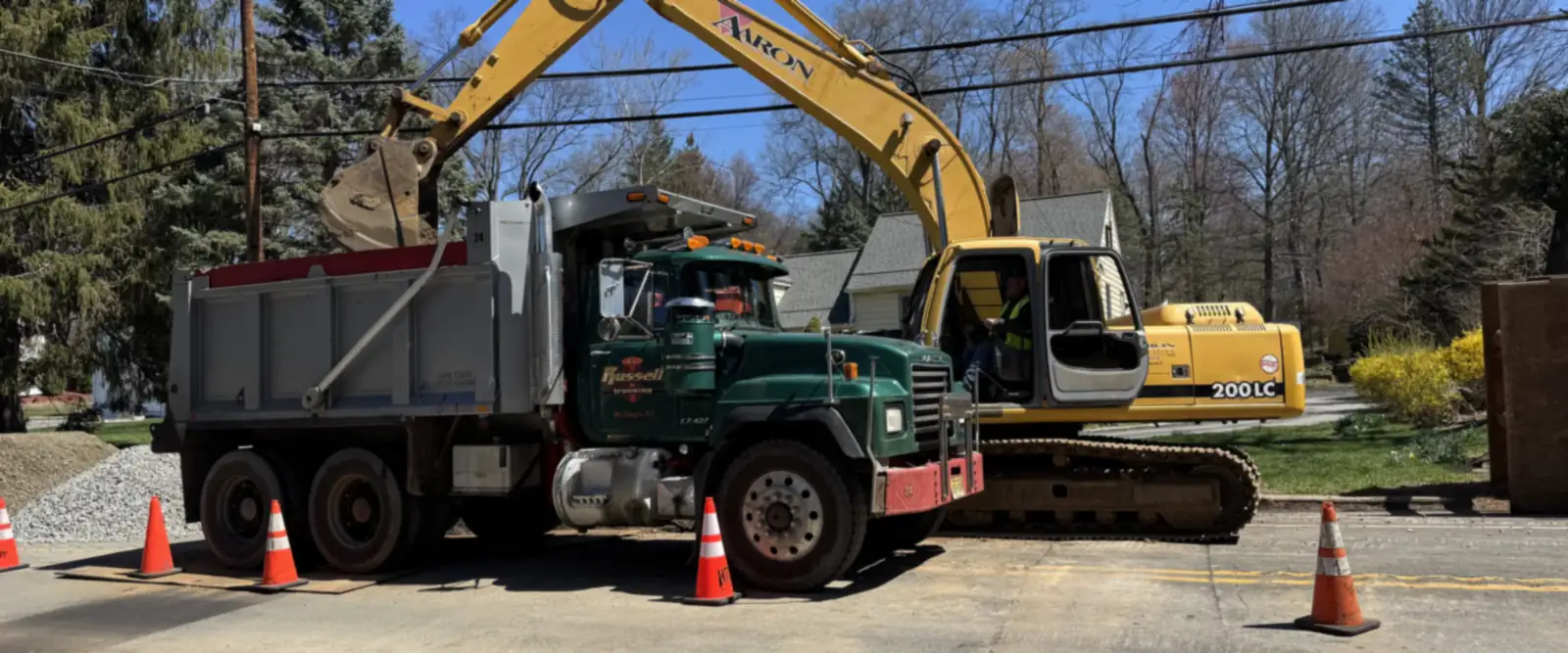 Aaron Excavating excavator and dump truck on a roadside job — commercial excavation near me