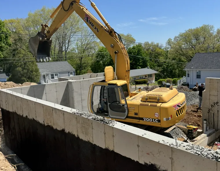 Aaron Excavating excavator backfilling around new foundation walls — residential excavation contractor