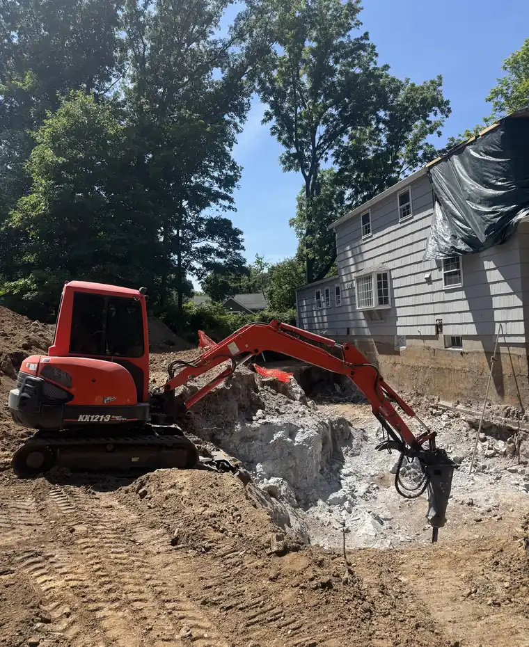 Mini excavator digging beside a home for a septic repair