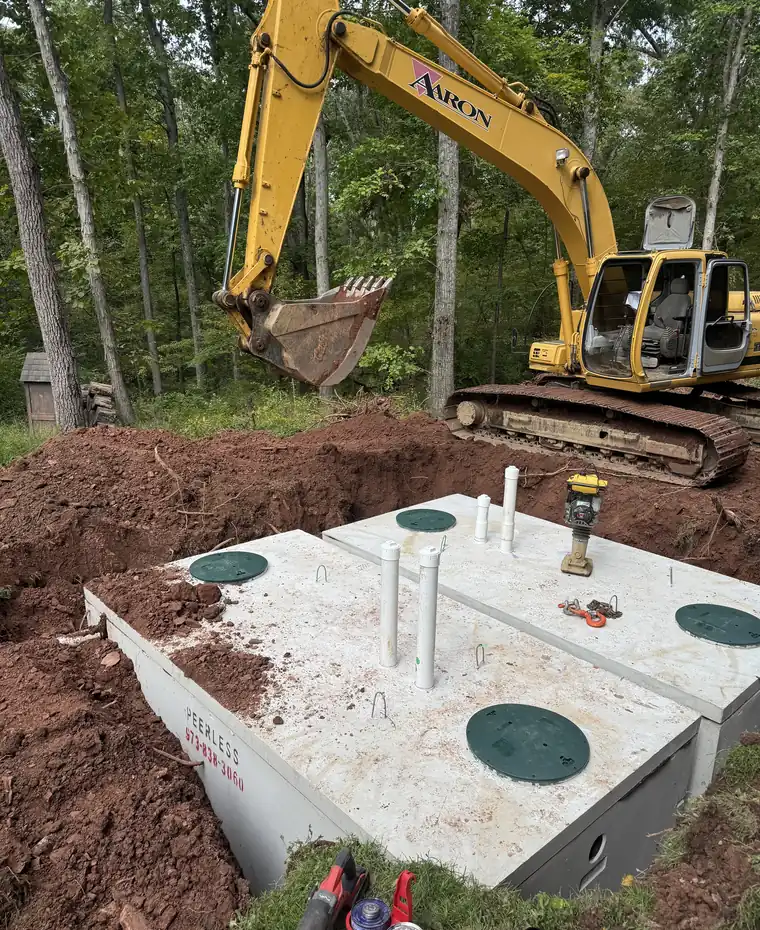 Aaron Excavating excavator setting a precast septic tank during septic tank installation