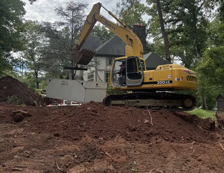 Aaron Excavating excavator grading a residential site beside a new home